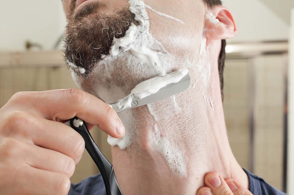 man shaving with razor