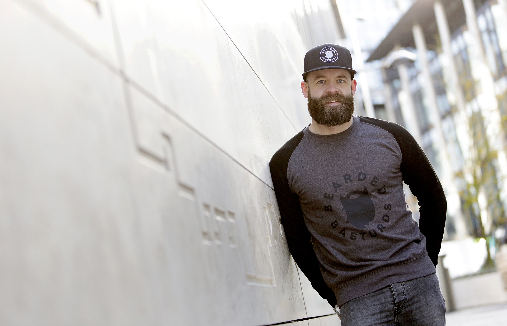 Man lying his shoulder to the wall is wearing a cap and with beautiful beard