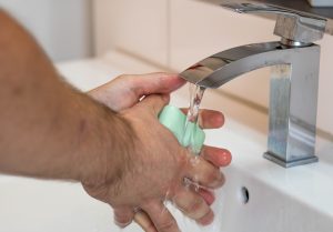man washing his hands with soap and running water
