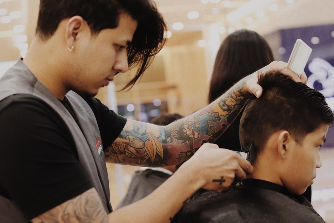 barber using clipper on boy