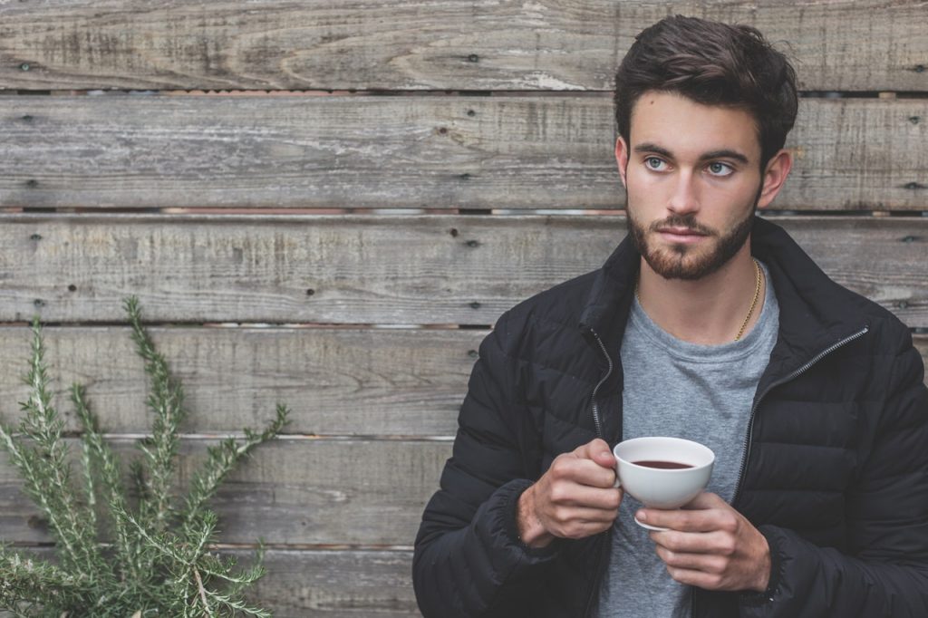 man with beard holding a cup of coffee